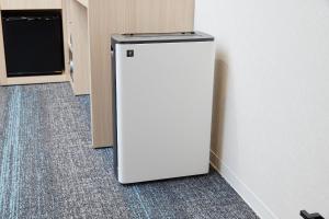einen weißen Kühlschrank in der Ecke eines Zimmers in der Unterkunft Henn na Hotel Premier Kagoshima Tenmonkan in Kagoshima