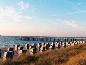 eine Reihe von Stühlen am Strand neben dem Meer in der Unterkunft Bastorf Sea View Escape in Bastorf