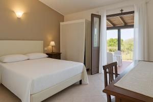 una camera da letto con un letto, un tavolo e un balcone di Agriturismo Nuraghe Tuttusoni a Aglientu
