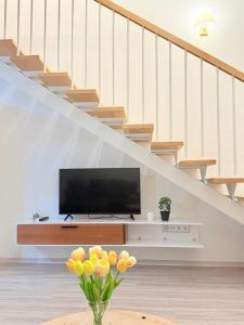 a living room with a tv and a vase with flowers at green diamond duplex in Tbilisi City +5 photos
