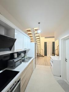 a kitchen with white cabinets and a staircase in the background at green diamond duplex in Tbilisi City
