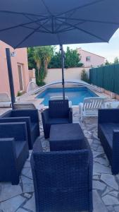een terras met stoelen en een parasol en een zwembad bij villa climatisée avec grande piscine in Saint-Laurent-de-la-Salanque