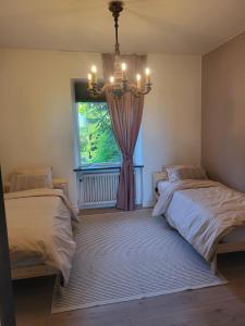 a bedroom with two beds and a window with a chandelier at Cosy and charming semi-detached house in Hilleshög in Härslöv