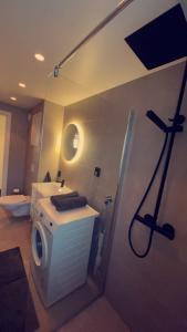 a bathroom with a shower and a washing machine at Penthouse apartment with sauna, balcony and free coffe in Bergen +14 photos