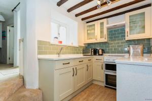 eine Küche mit weißen Schränken und einer Spüle in der Unterkunft Cosy North Devon Thatched Cottage near beaches in Marwood + 29 Fotos