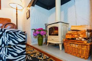 ein Wohnzimmer mit einem Kamin und einer Vase aus Blumen in der Unterkunft Cosy North Devon Thatched Cottage near beaches in Marwood
