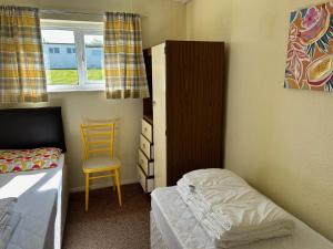 a small bedroom with a bed and a chair at Bungalow 19 Widemouth Bay in Poundstock