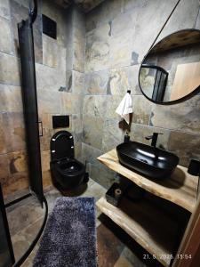 a bathroom with a black toilet and a sink at Vikendice Dream 1 in Sekulić  +17 photos