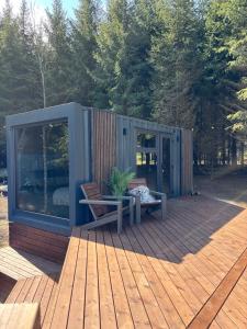 una casa pequeña sentada en una terraza de madera en Sidrabgrava - Luxury cabin in woods, en Limbaži