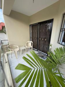a balcony with two chairs and a plant at HEA Stays II in San Felipe de Puerto Plata