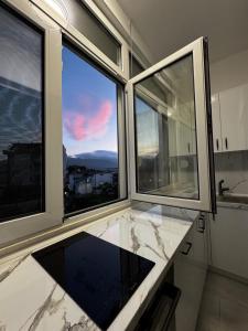 a kitchen with large windows with a view of the city at Mira's Apartment in Shkodër +13 photos