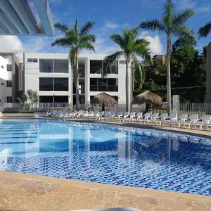 a swimming pool with chairs and palm trees and a building at Ciudadela Santafé De Antioquia in Santa Fe de Antioquia