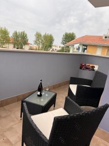 eine Terrasse mit Stühlen und einem Tisch mit einer Flasche Wein in der Unterkunft Nicole in Francavilla al Mare