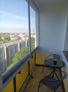 Una mesa pequeña y una silla en una habitación con ventana en DebRentZen Station Apartman - business plus, en Debrecen