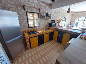 a kitchen with wooden cabinets and a stainless steel refrigerator at Villa Des Arts in Essaouira +12 photos