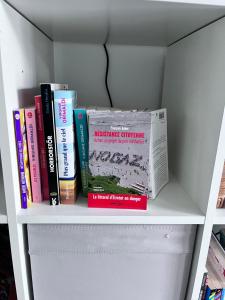 eine Gruppe von Büchern auf einem Regal in der Unterkunft Les gites Inclusifs d'OMAOMA in Saint-Jouin-Bruneval