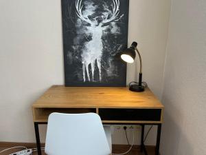 a desk with a lamp and a white chair at Der grüne Fürst Ferienwohnung Apartment 2 in Bad Muskau