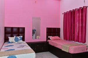 een roze kamer met 2 bedden en een spiegel bij The Sunrise Ayodhya Guest House in Ayodhya