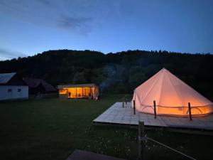 een tent in een veld met een huis op de achtergrond bij Glamping - Casuta de pe Fiad in Romuli +14 foto's