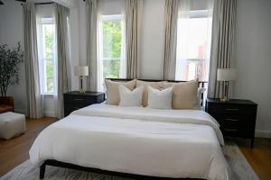 a bedroom with a large white bed with windows at St. Louis Luxury Home 3BR/3.5BA Near Everything in Soulard