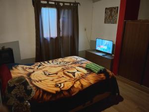 a bedroom with a tiger patterned bed with a television at Dpto BBB in Zapala
