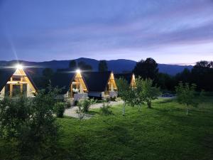 a house in a field with mountains in the background at Resort La Familia in Bihać