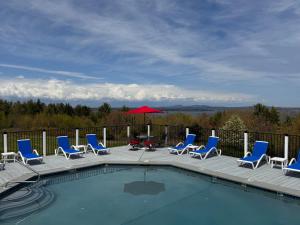 a pool with chairs and a table and an umbrella at Acadia Ocean View Hotel in Bar Harbor