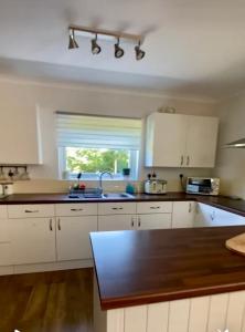 a kitchen with white cabinets and a sink and a window at Detached Home Close to the Beach Newquay in Saint Columb Minor