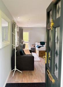 a living room with a black couch and a bed at Lakeside Cabin on Stilts- 'Kingfisher' in Rous Lench