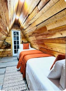 two beds in a room with a wooden wall at 9,000 feet Retreat Above It All in Guffey