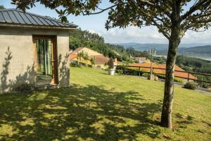 a house with a tree in a grassy yard at Casa El Gabinete in Cariño