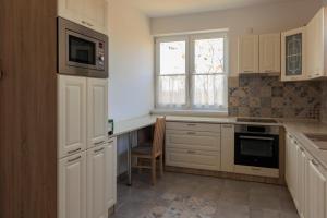 a kitchen with white cabinets and a table and a window at Lesi Vendégház in Hajdúböszörmény