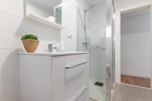 a white bathroom with a sink and a shower at Soleado apartamento en el centro de la ciudad in Santander