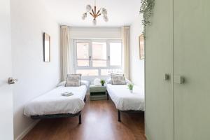 a room with two beds and a window at Soleado apartamento en el centro de la ciudad in Santander