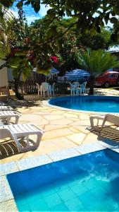 a swimming pool with chairs and a table and chairs at Pousada Aquarela Pirenopolis in Pirenópolis