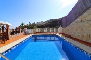 a swimming pool with blue water in front of a building at Villa Alabarce Nerja by Spain Sun Rentals in Nerja