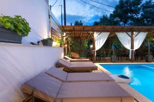 a swimming pool with benches next to a house at Kipos Resort in Nea Peramos