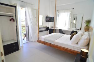 a bedroom with a bed with white sheets and pillows at Axilleion Boutique Hotel in Ermoupoli +52 photos