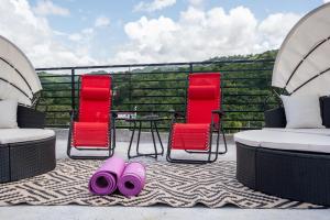a patio with two chairs and a table and pink slippers at Palms Rooftop Villa in Ocho Rios