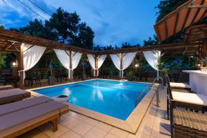 an outdoor swimming pool with a pergola and patio furniture at Kipos Resort in Nea Peramos