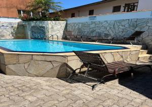 a swimming pool with a bench and a chair next to it at Chales Camburi in Camburi