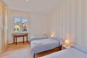 a room with three beds and a table and a window at Porto Santo Stefano Panoramic Penthouse in Porto Santo Stefano