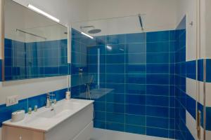 a blue tiled bathroom with a sink and a mirror at Porto Santo Stefano Panoramic Penthouse in Porto Santo Stefano +11 photos