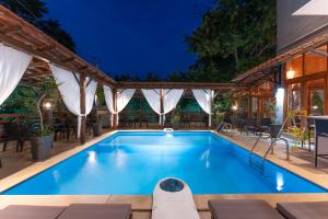 a swimming pool with tables and chairs around it at Kipos Resort in Nea Peramos