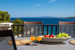 a table with a bowl of fruit and two glasses of juice at Apartments Doro in Vela Luka