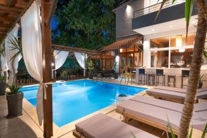 an indoor pool with lounge chairs and a house at Kipos Resort in Nea Peramos