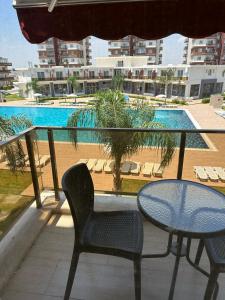a balcony with a table and chairs and a pool at Kıbrısın gözdesi Long Beach de Havuz manzaralı stüdyo daire in Trikomo