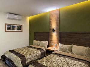 Zwei Betten in einem Hotelzimmer mit grünen Wänden in der Unterkunft Hotel Los Valles Plus in Creel