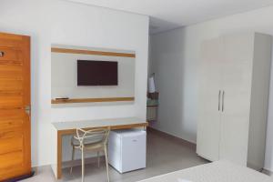 een slaapkamer met een bureau en een tv aan de muur bij Novo Valle Hotel in Itinga