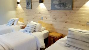 two beds in a room with white sheets and pillows at Hotel Bacaris in Puerto Tranquilo